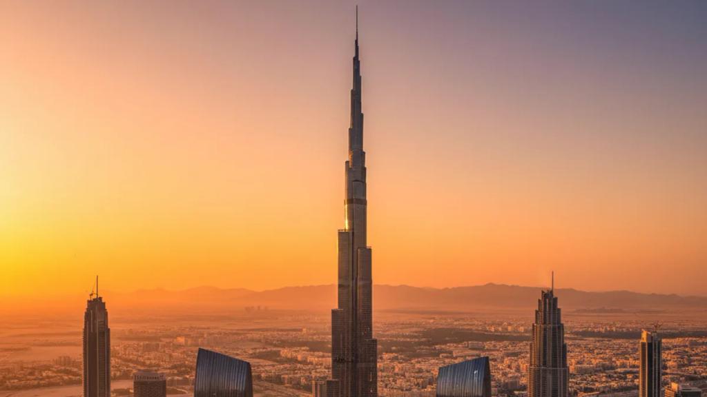 Traveller by the Dubai skyline at dusk checking a phone showing a connected mobile signal