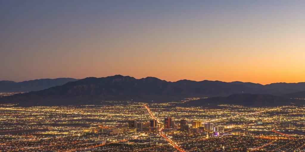 The glowing desert valley of Las Vegas at dusk, the Strip's neon towers rising from the Mojave